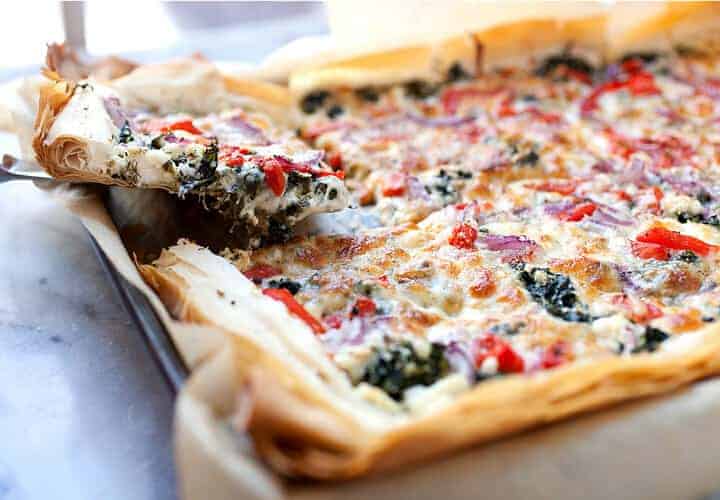 Spanakopizza: A perfect mash-up between flaky spanakopita and a delicious pizza. Loaded with spinach, feta, and roasted red peppers, but it still has a flaky phyllo dough crust! Great for a meal or appetizer. | macheesmo.com