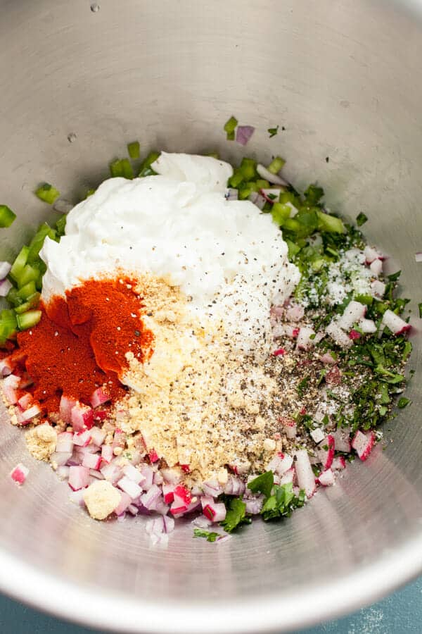 Adding the dressing to crunchy potato salad ingredients.