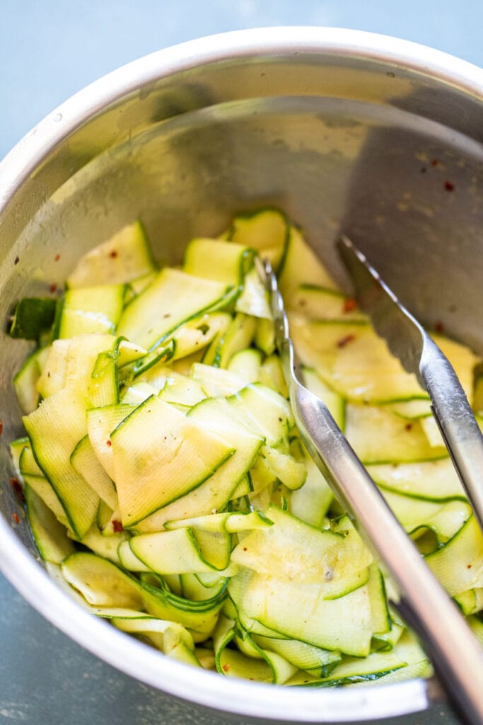 Tossing zucchini with dressing.