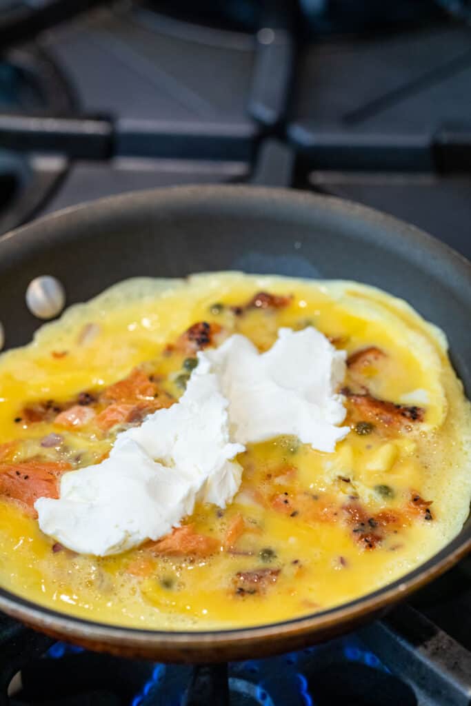 Adding cream cheese to the omelette.