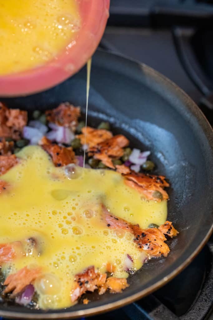 Adding eggs to skillet for omelette.