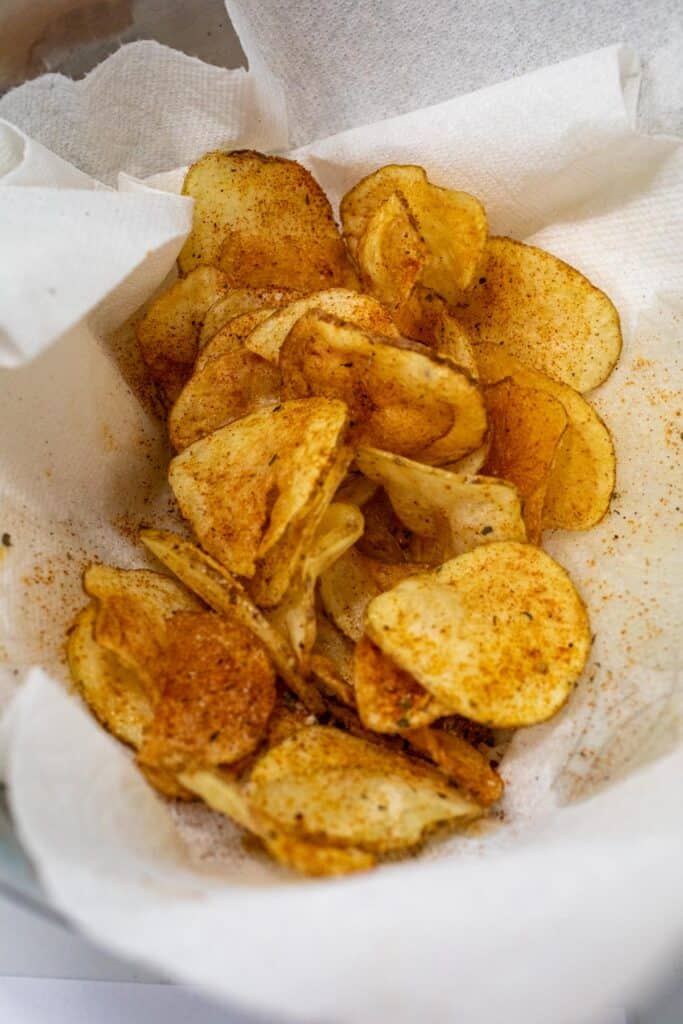 Draining and seasoning the chips after frying.