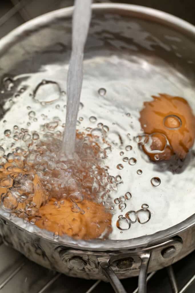 Running eggs under cold water to stop cooking.