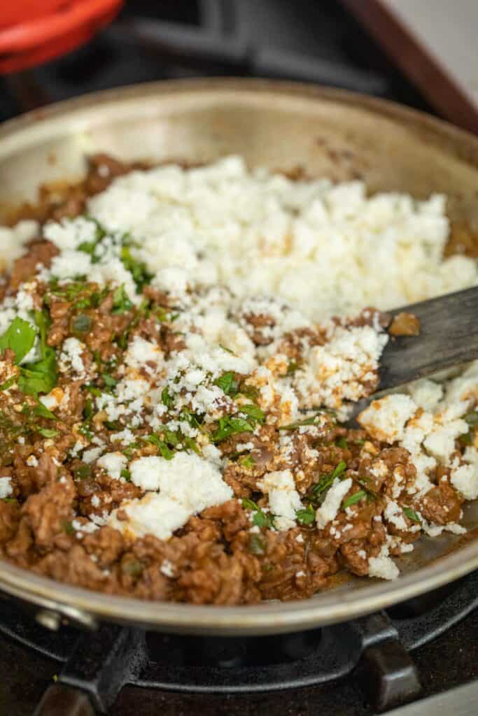 Folding in cheese to beef filling.