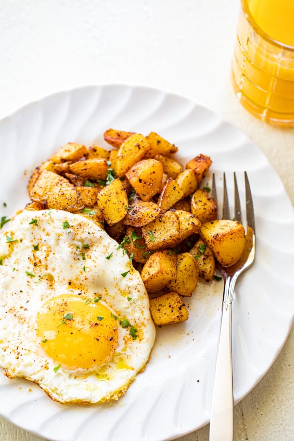 Home fries on a plate with a side of sunny side up eggs.