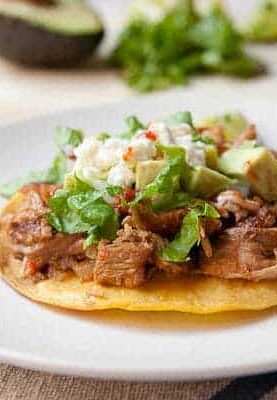 Traditional pork tinga simmered with peppers and spices and served on tostadas with classic toppings. Via Macheesmo.