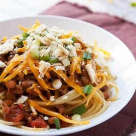 A classic cincinnati chili version with beef and bean chili served over plain spaghetti with lots of great toppings like shredded cheese, scallions, and crackers. Chili never tasted so good!