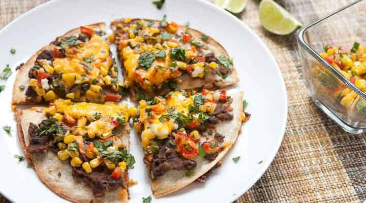 Black Bean and Corn Tortilla Tart: A half quesadilla and half pizza meal that's easy to make but different from your standard Tex-Mex recipe. Layers of black beans mashed with spices and a fresh corn salsa with two kinds of cheese and baked until crispy.