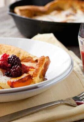 Fresh Peach Dutch Baby: In-season, perfect peaches cooked with a fluffy pancake in a cast iron skillet and served with a quick berry syrup. A perfect late summer breakfast! | macheesmo.com