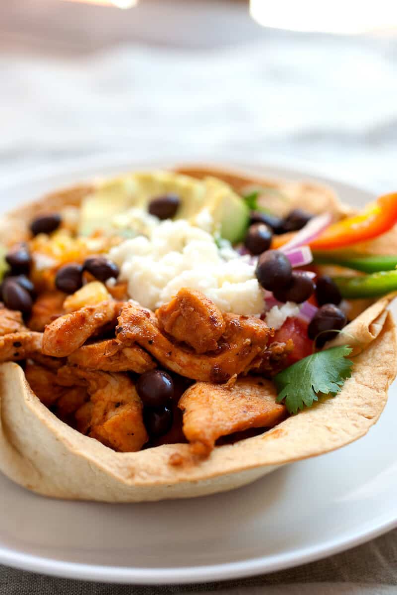 Chipotle Chicken Taco Bowls! I don't mean Chipotle like the restaurant, these chicken taco bowls are so much better! Spicy chipotle chicken layered with corn, black beans, cilantro rice, and other great taco toppings in an edible taco bowl! | macheesmo.com