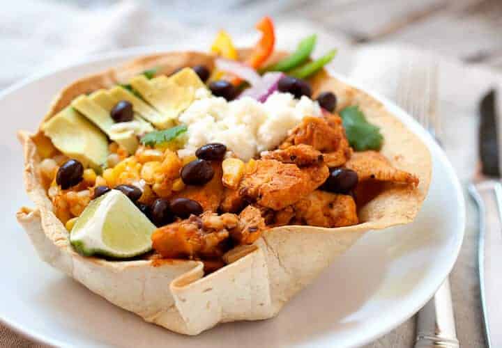 Chipotle Chicken Taco Bowls! I don't mean Chipotle like the restaurant, these chicken taco bowls are so much better! Spicy chipotle chicken layered with corn, black beans, cilantro rice, and other great taco toppings in an edible taco bowl! | macheesmo.com