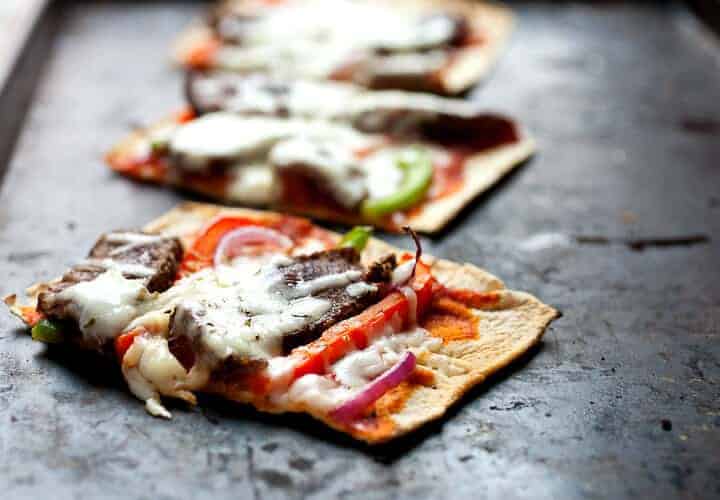 Cheesesteak Flatbread: Flatbreads topped with sliced sirloin steak, peppers, onions, and provolone cheese. Great as a meal or a hearty appetizer. Super easy to make thanks to Flatout Flatbread pizza crust! #sponsored | macheesmo.com