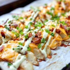 Loaded Potato Wedges - Appetizer? Side dish? Main meal? These completely loaded baked potato wedges can be anything you want. Cheddar, chives, and an avocado sour cream sauce. Potato perfection! | macheesmo.com
