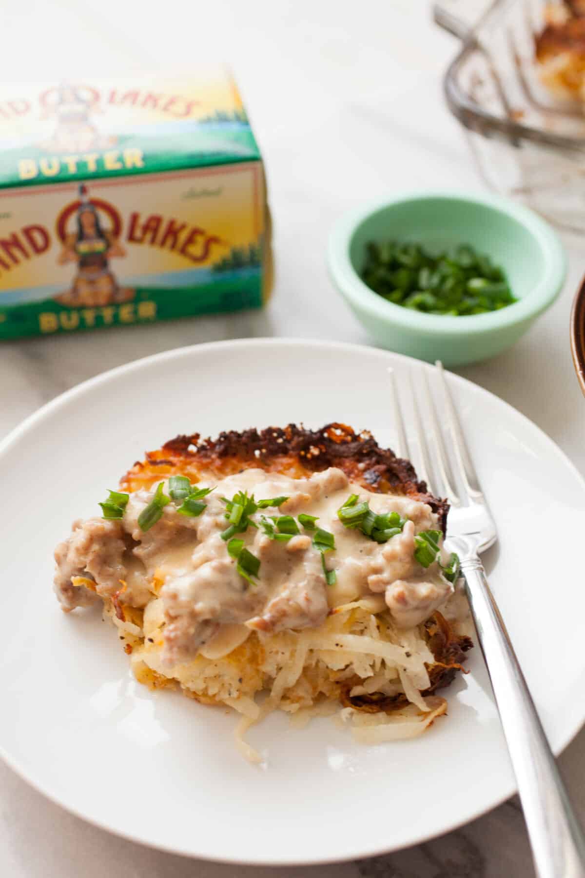 Potato Casserole with Sausage Gravy: This is slow comfort food at its best. Homemade simple potato casserole with fresh potatoes topped with a hearty sausage gravy. Comfort food on a plate! | macheesmo.com