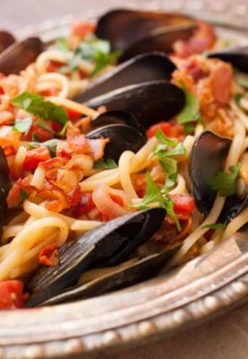 Spicy Mussel Linguine: This is a classic Italian dish packed with fresh mussels plus a light tomato sauce and crispy bacon. Surprisingly easy to make and so delicious. Don't forget the bread! | macheesmo.com