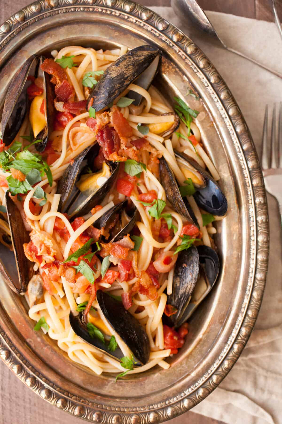 Spicy Mussel Linguine: This is a classic Italian dish packed with fresh mussels plus a light tomato sauce and crispy bacon. Surprisingly easy to make and so delicious. Don't forget the bread! | macheesmo.com