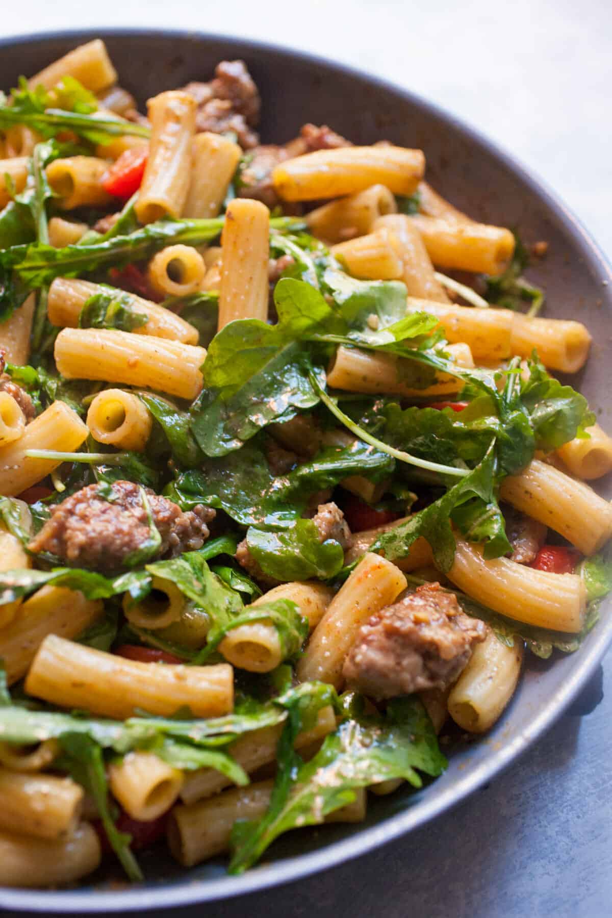 Easy Pesto Pasta with Sausage: This pasta dish is perfect comfort food. Simple flavors with sweet Italian sausage, arugula, and grape tomatoes, tossed with pasta and pesto. One of my new favorites! | macheesmo.com