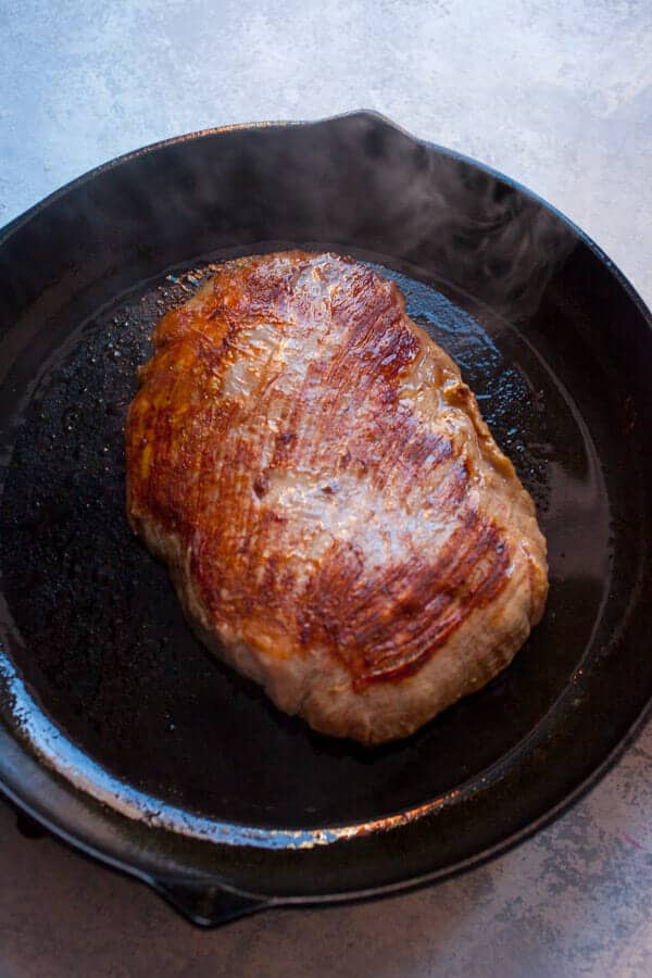 Caramelizing flank steak in a cast iron skillet.