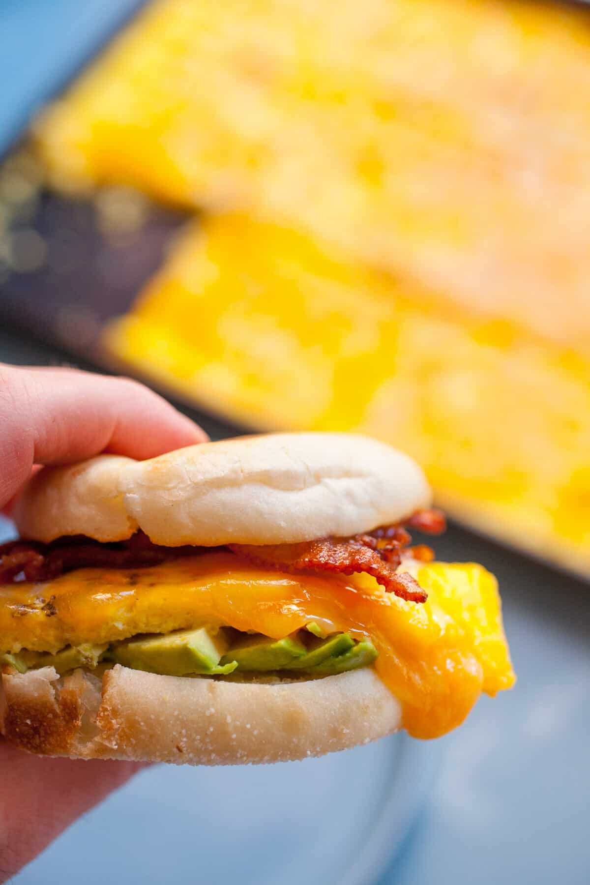 These Sheet Pan Breakfast Sandwiches are perfect for quick weekday breakfasts. They freeze/reheat perfectly. I make mine with fluffy baked eggs, cheese, avocado, and bacon! macheesmo.com