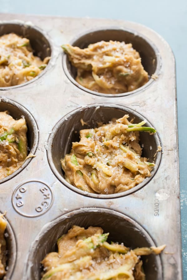 Zucchini muffins in a pan with coarse sugar on top.