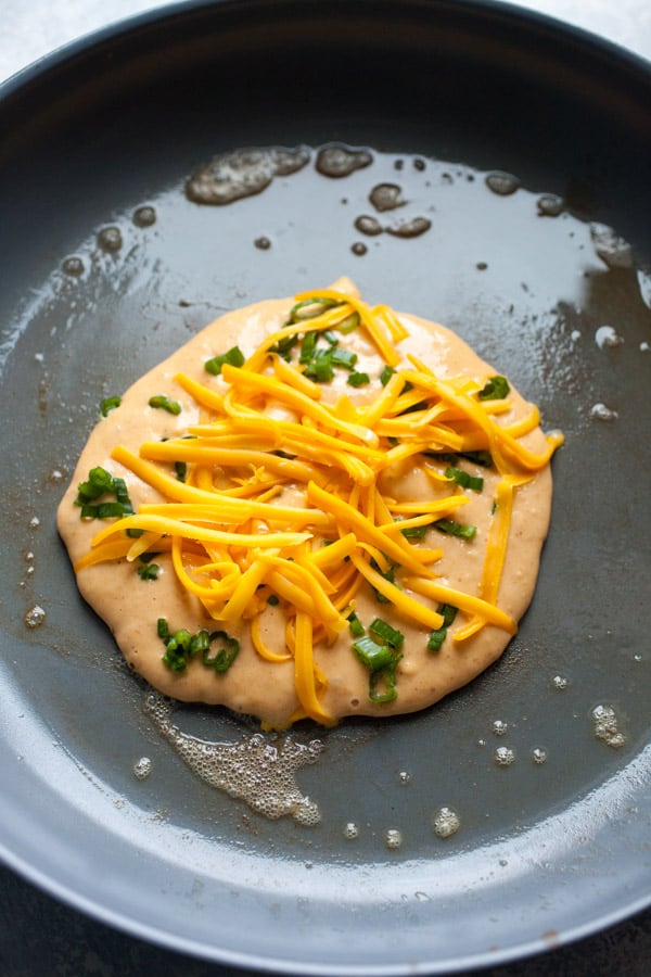Adding cheese and scallions to pumpkin pancakes.