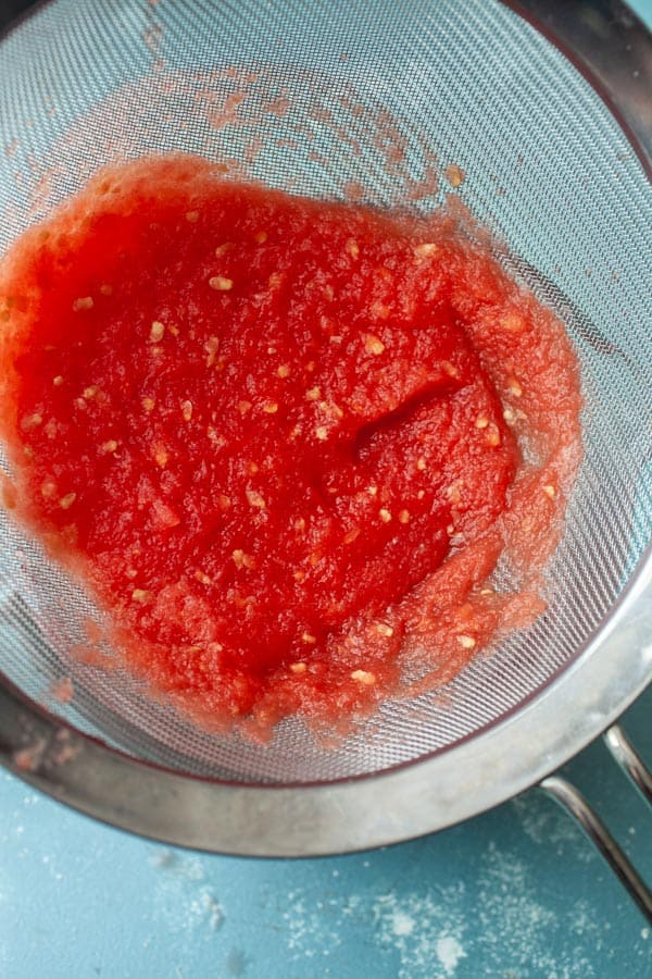 Straining watermelon pulp for fresh juice.