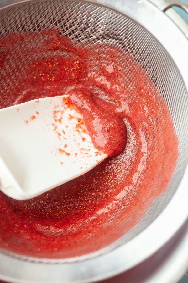 Straining the strawberries to remove the seeds.