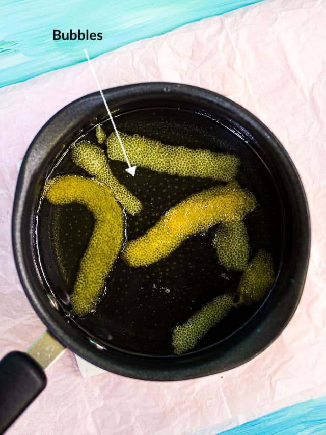 A saucepan with simple syrup and lemon peels