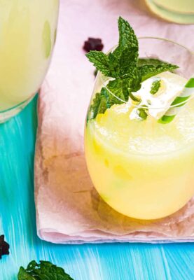 A glass of lemonade with a mint garnish and a green-white striped straw