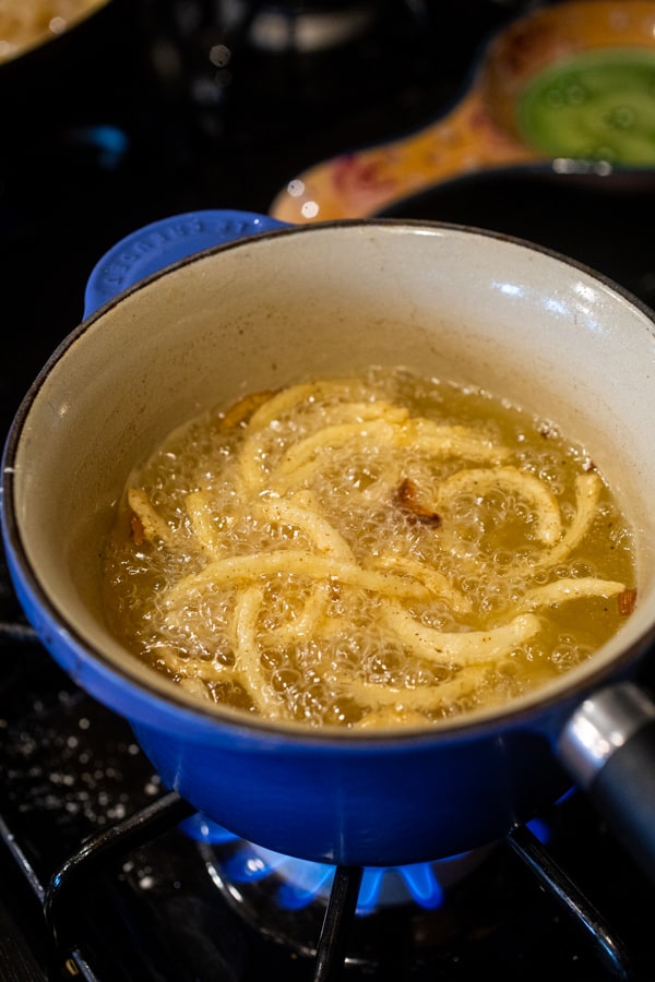 Frying onion strings for sausage dogs.
