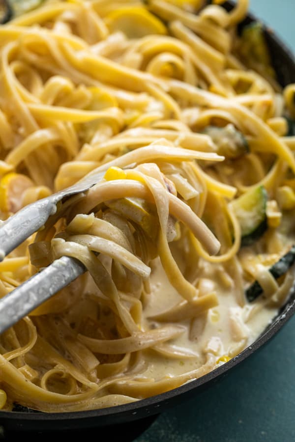 Tossing together fettuccine alfredo with summer vegetables.