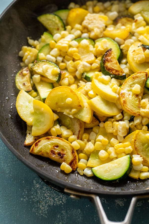 Adding corn to vegetables for fettuccine.