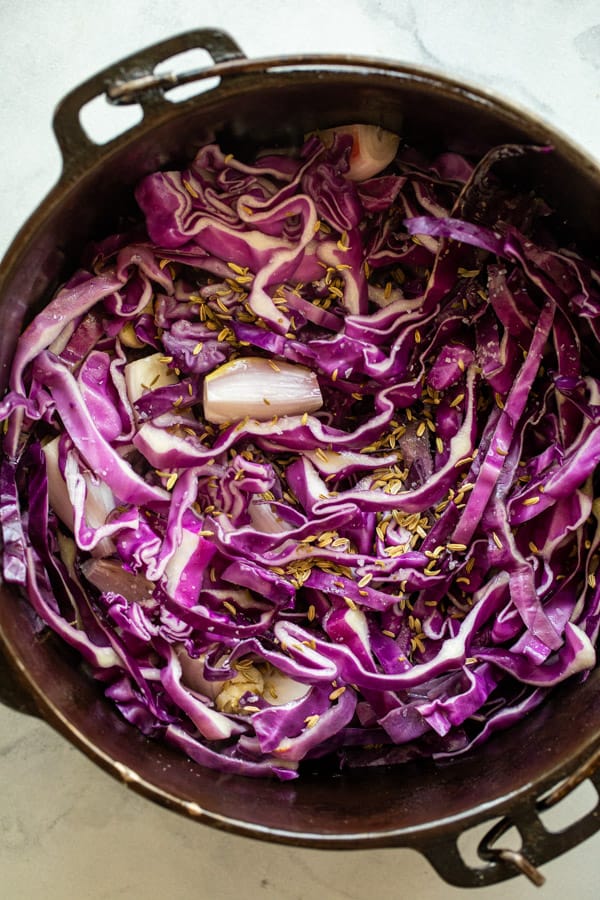 Adding cabbage to skillet for braised apples.