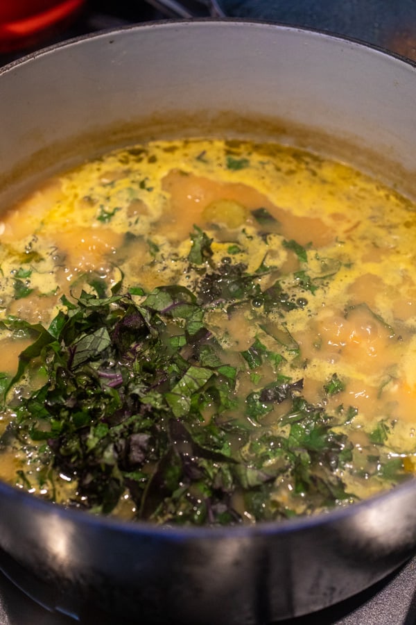 Adding kale to white bean soup.