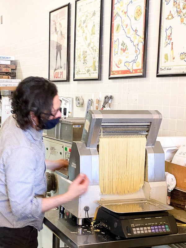 A man feeding pasta through a pasta-cutting machine