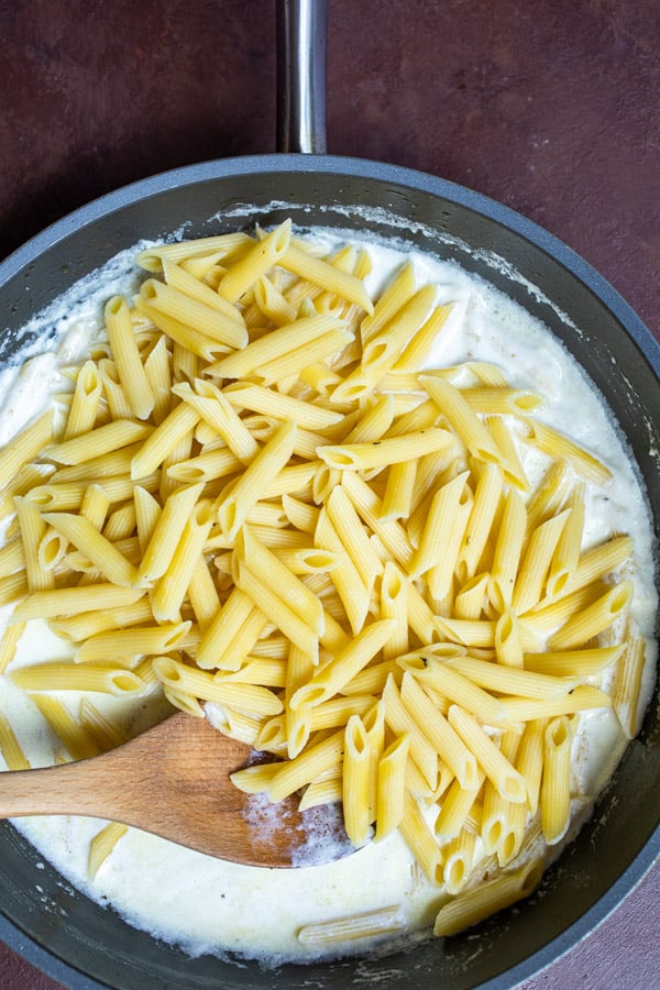 Penne added to alfredo sauce.
