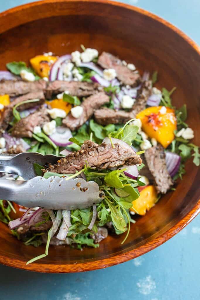 Tongs with grilled steak salad.