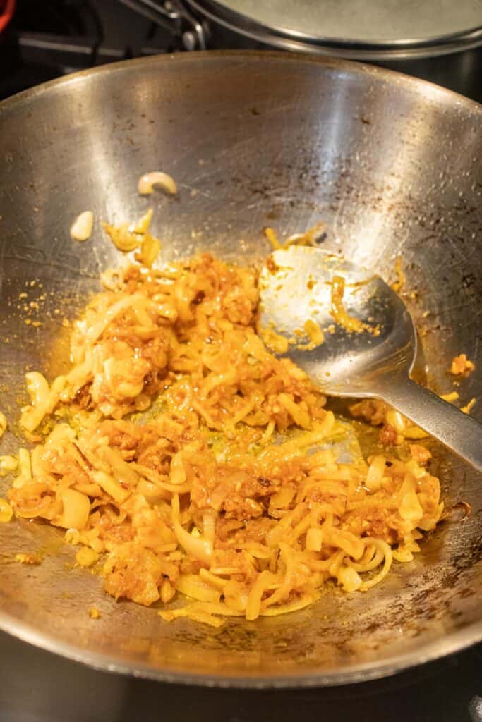 Adding panang curry paste to wok.