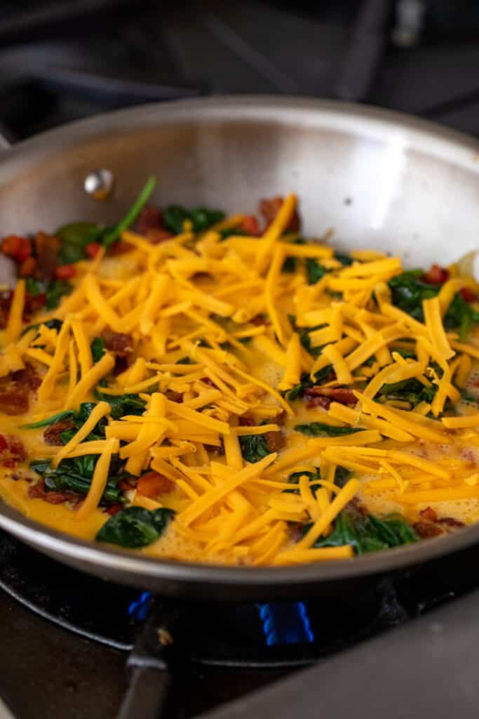 Adding egg and cheese to skillet.
