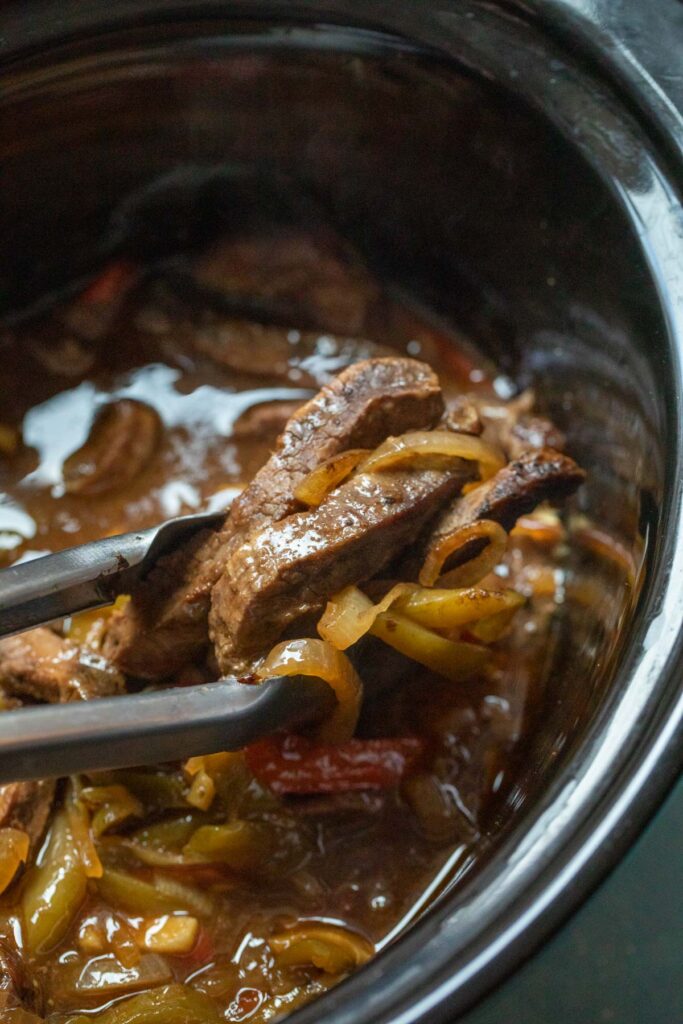 Slow cooker cooking pepper steak.