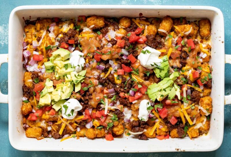 Tater Tot Nachos! It's exactly what you're thinking. Baked Tater Tots topped with cheese, green chile sauce, chorizo, and all the traditional nacho toppings! macheesmo.com
