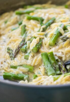 Creamy orzo with asparagus in a skillet.
