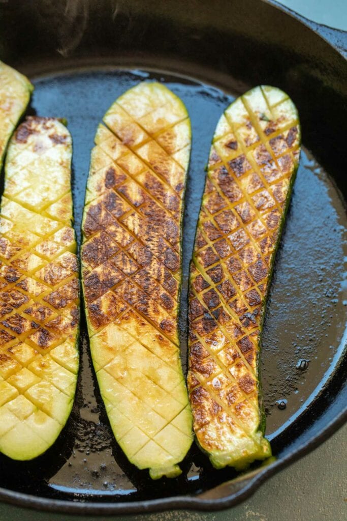Searing zucchini in a skillet.
