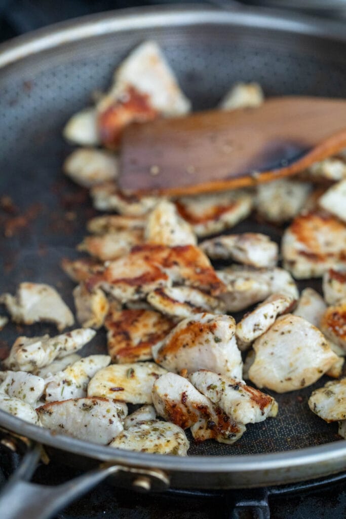 Chicken seasoned and cooking in a skillet.