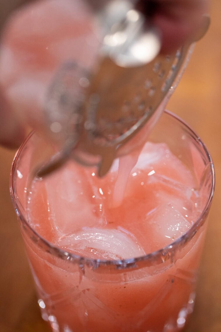 Straining the cocktail into a glass.
